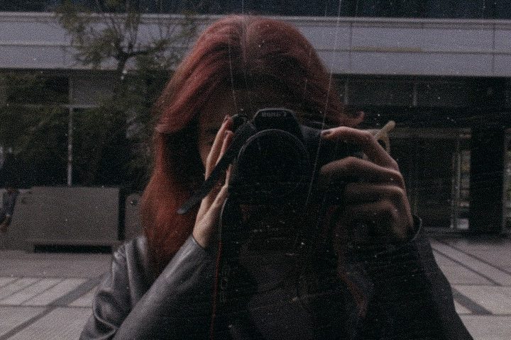 Self-portrait with a camera in a window reflection