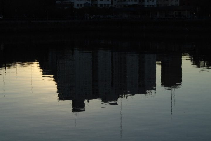 City reflected in dark water at dusk